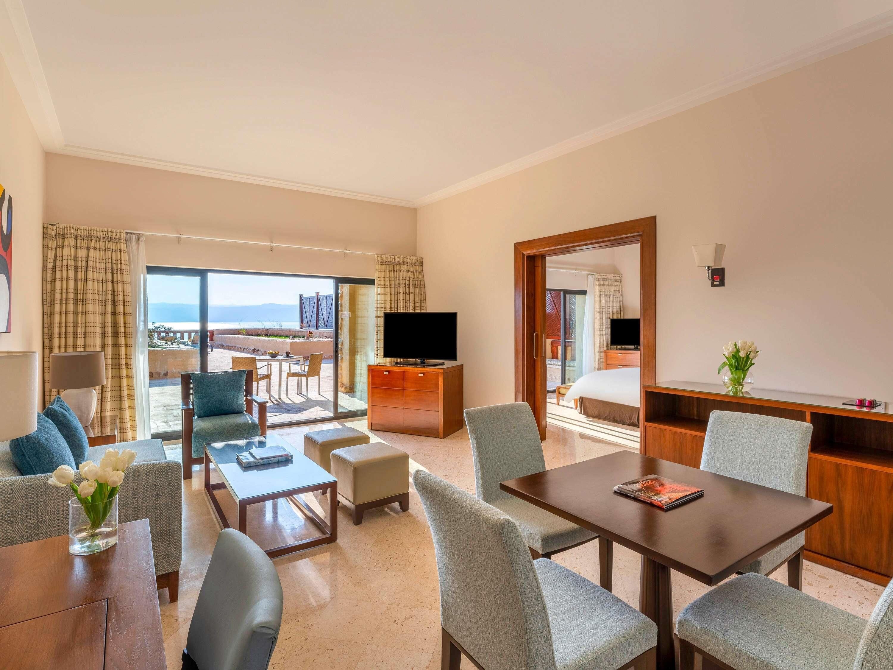 Ein Hotelzimmer mit Balkon, Fernseher, Esstisch und Bett.