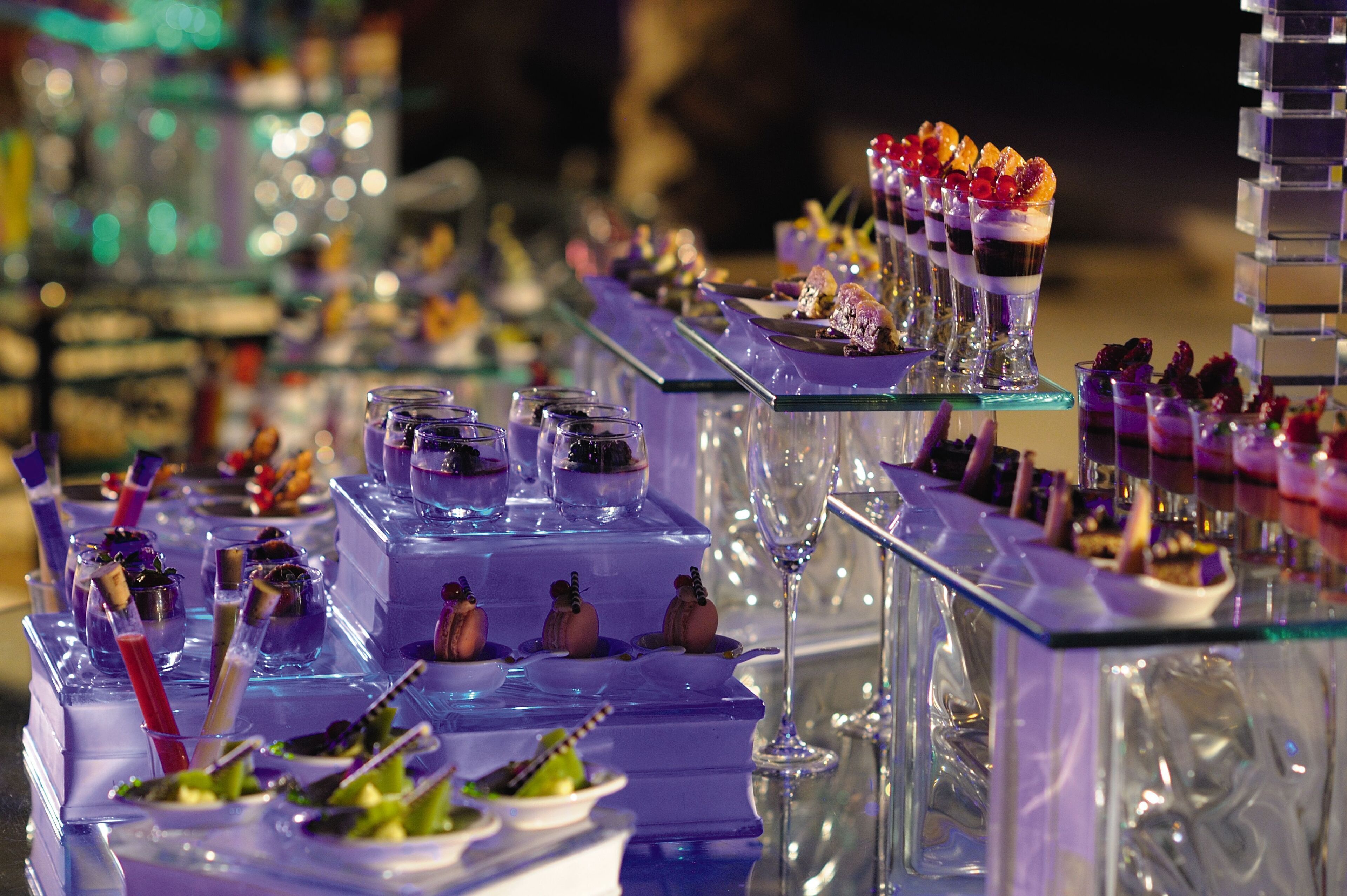 Variedad de postres y bebidas sobre una mesa de vidrio, probablemente en un hotel o evento.