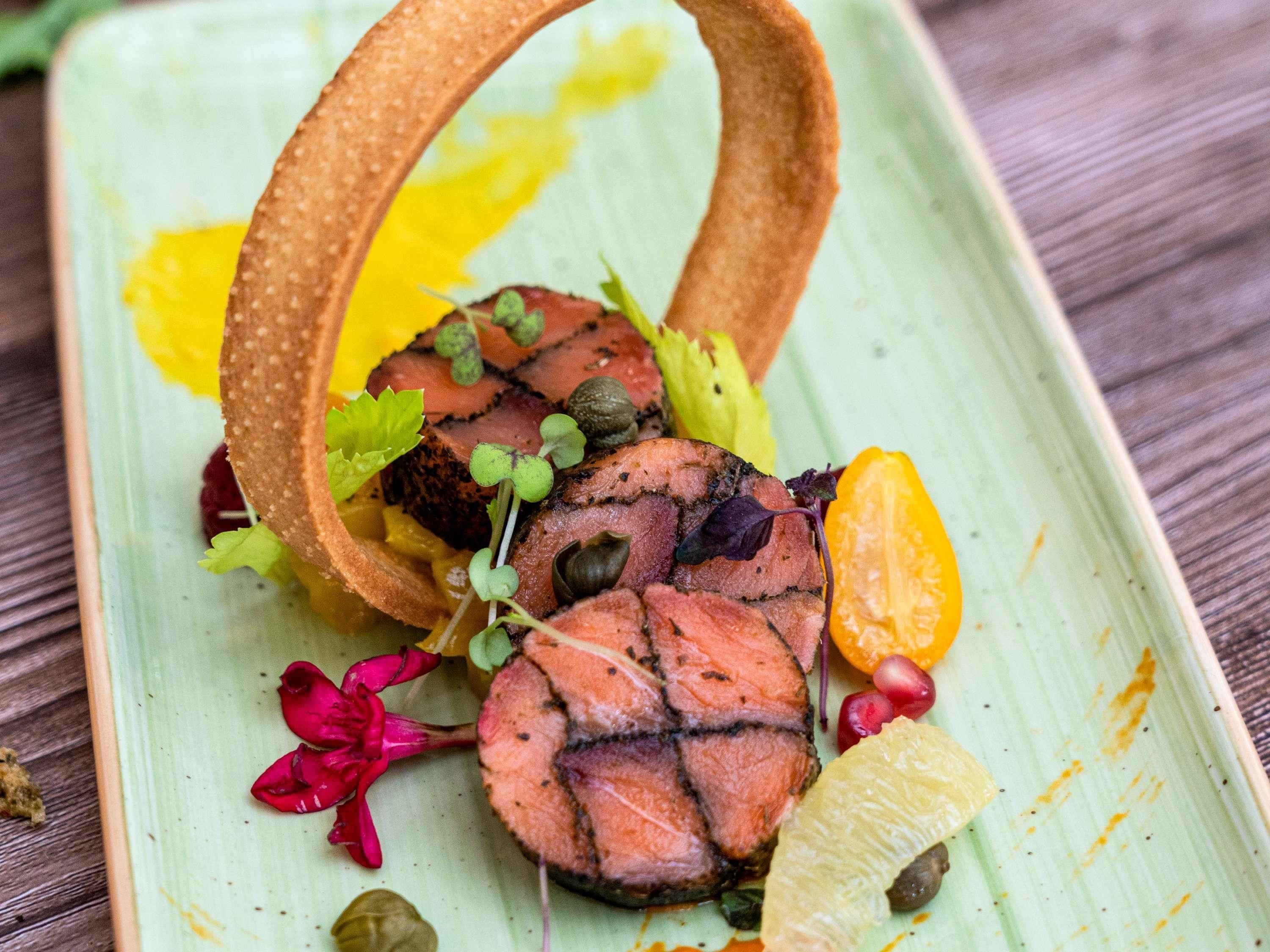 Un plato con carne cortada, verduras y un adorno circular.