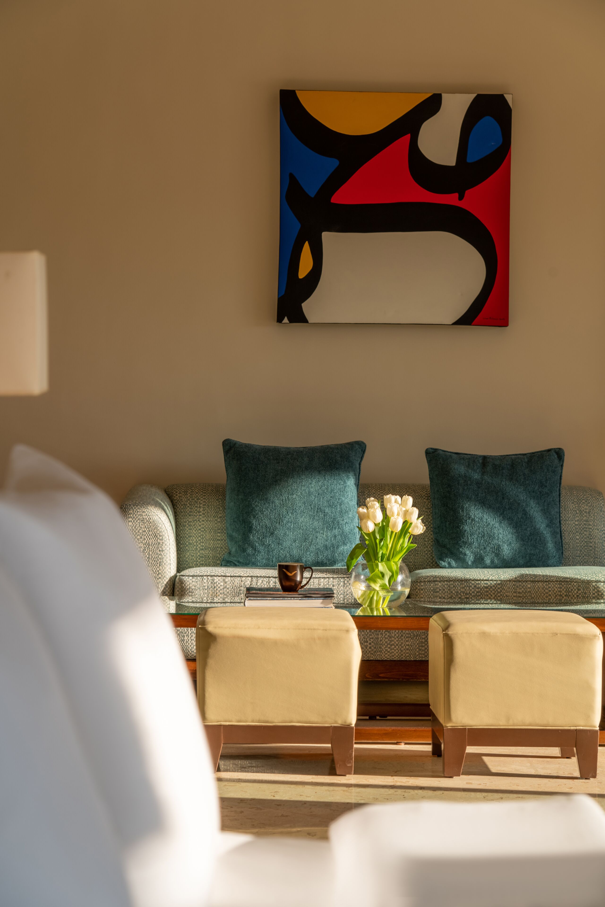 Un salon comprenant un canapé, deux fauteuils, une table basse et un vase de fleurs.