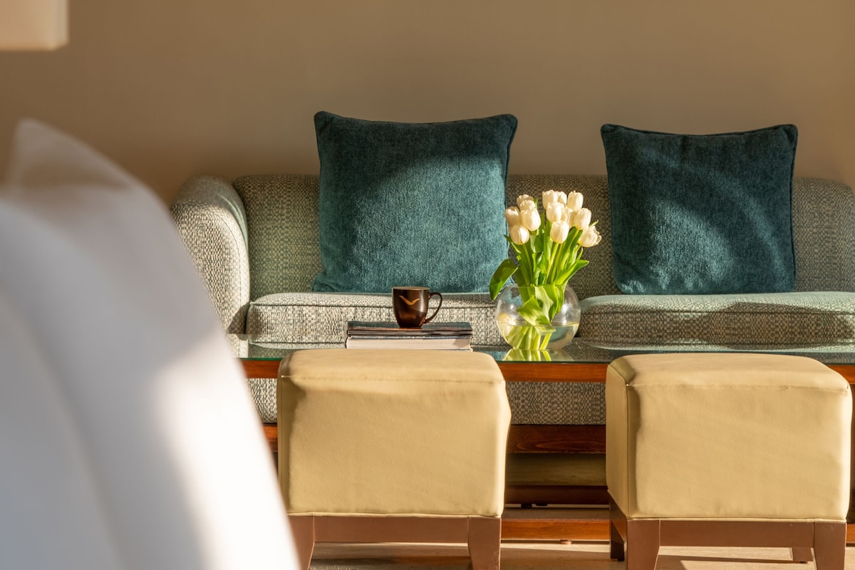 A living room with a sofa, two armchairs, a coffee table, and a vase of flowers.