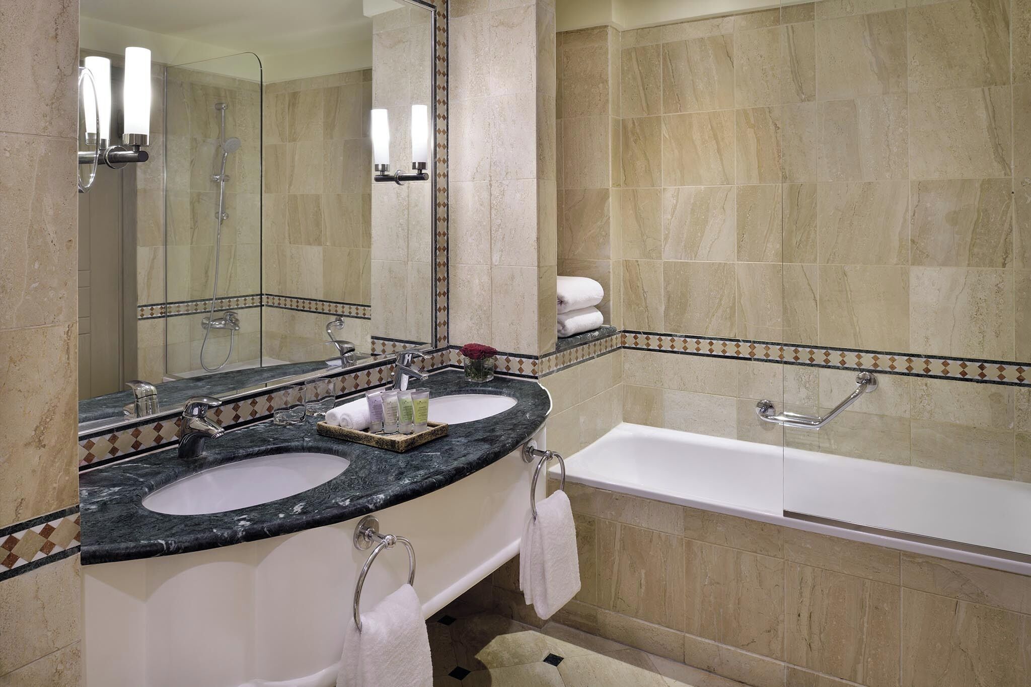 Un baño con dos lavamanos, una bañera y un espejo grande.