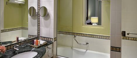 A bathroom with a bathtub, a sink, a mirror, and a window.