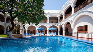 A swimming pool with blue water, surrounded by white arches and blue umbrellas. - Holiday Inn Express Veracruz Centro Historico (Veracruz)