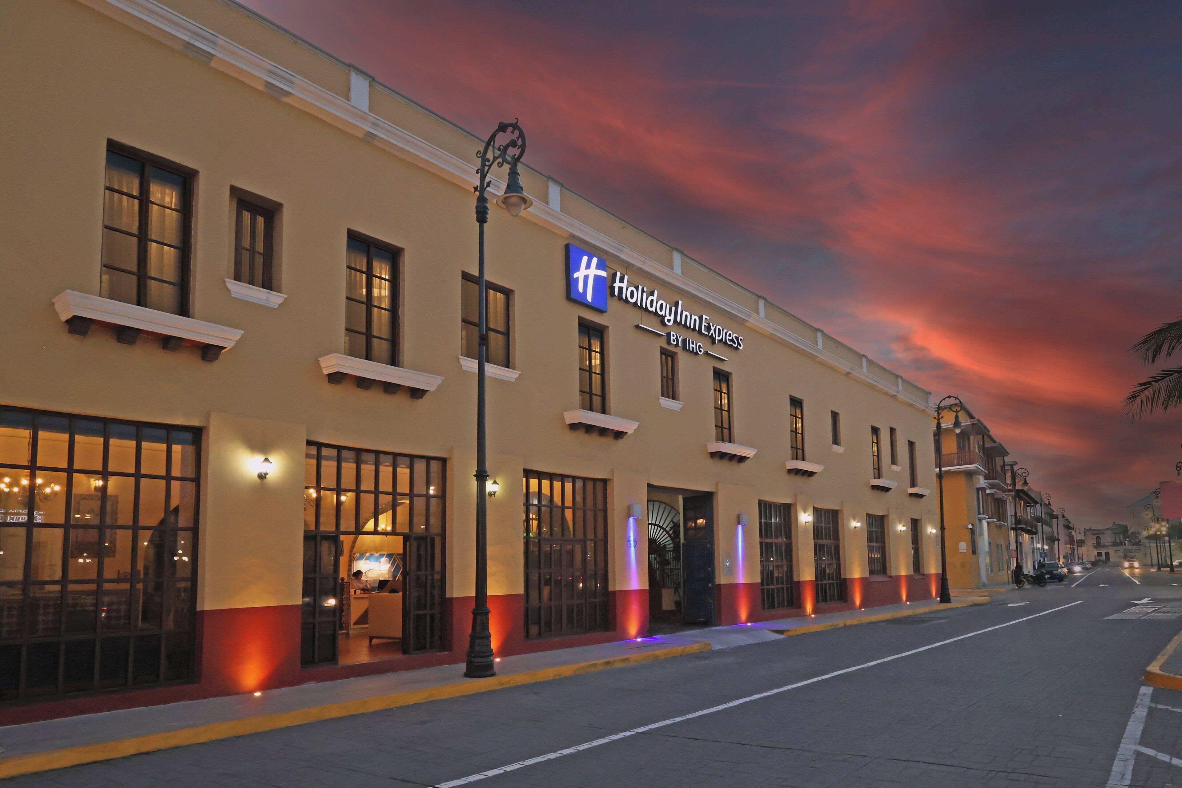 Un hotel Holiday Inn Express con una fachada clásica, ventanas amplias y un letrero llamativo.