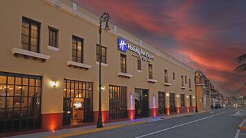 Un hotel Holiday Inn Express con una fachada clásica, ventanas amplias y un letrero llamativo.