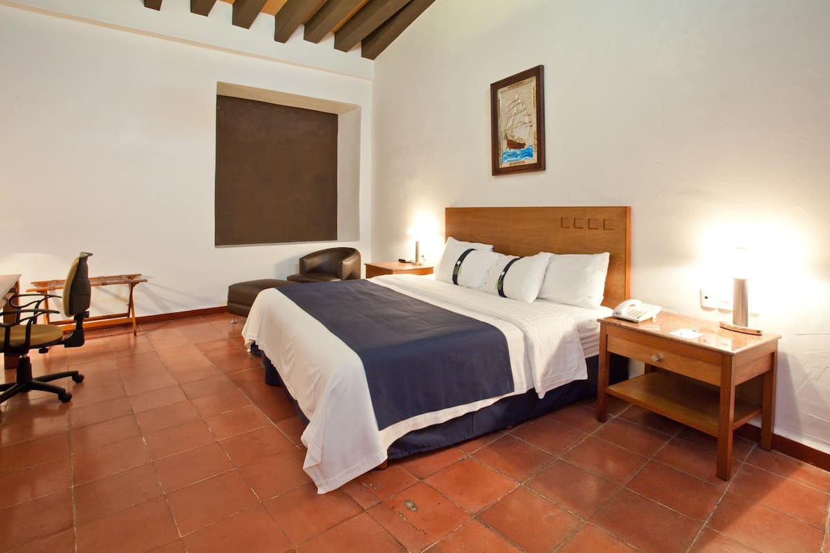 A hotel room with a bed, a desk, a chair, and a nightstand.