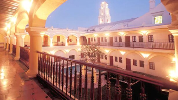 An architectural corridor with arches and a balcony railing, leading to a building with a clock tower. - Holiday Inn Express Veracruz Centro Historico (Veracruz)