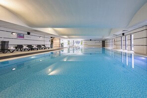 An indoor swimming pool with clear blue water, sun loungers along the sides, and a view of the outside through large windows. - Crowne Plaza Liverpool City Centre by IHG (Liverpool)