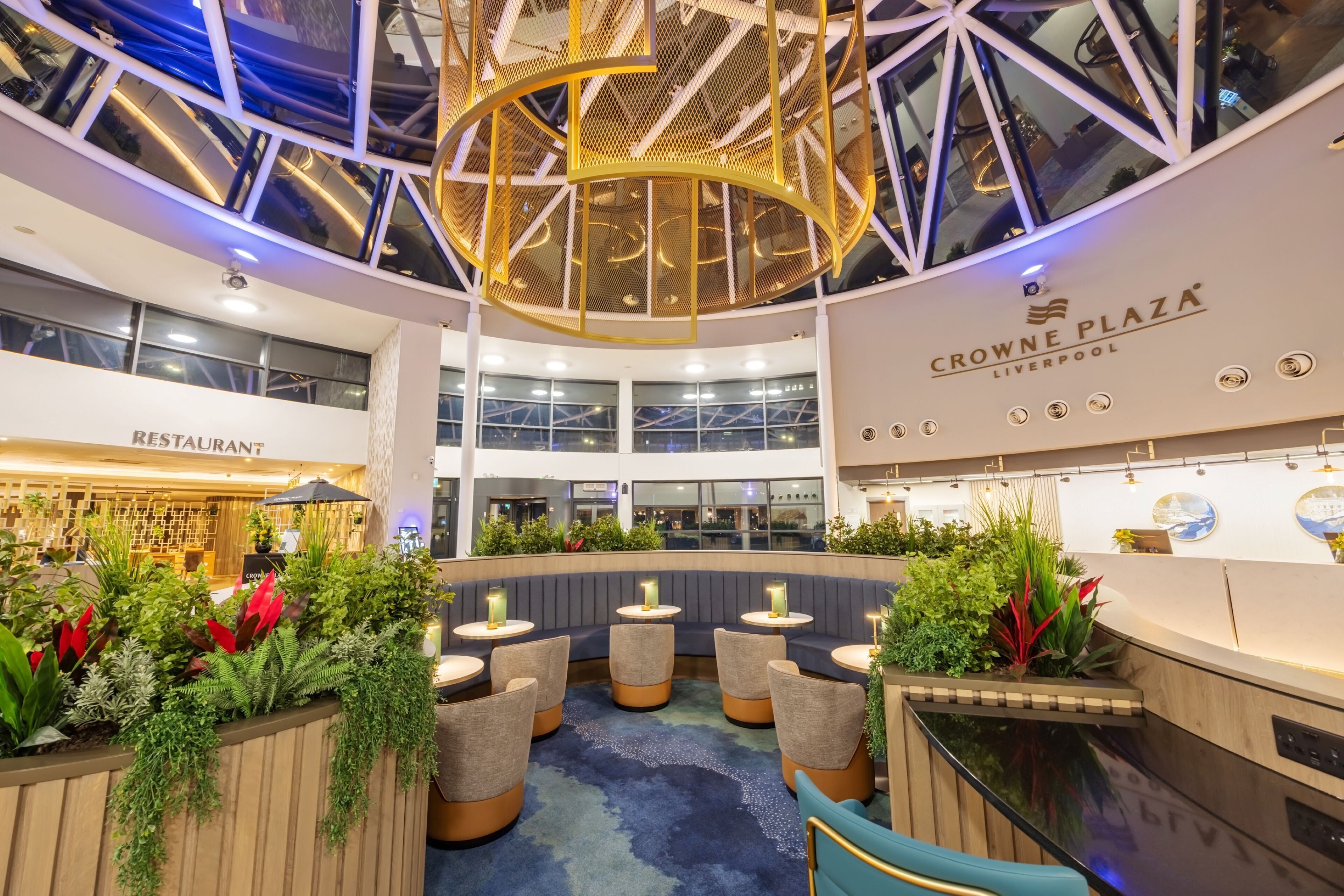 Un interior moderno con zonas de estar, un restaurante y un cartel de Crowne Plaza Liverpool.