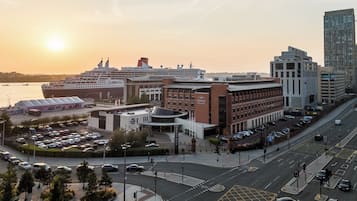 Um cruzeiro atracado num porto com um edifício moderno identificado como "Crowne Plaza" por perto.