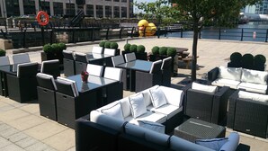 Outdoor seating with tables and chairs, a yellow duck sculpture, and a river view. - Crowne Plaza Liverpool City Centre by IHG (Liverpool)