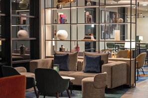 A modern lounge area with sofas, chairs, a bookshelf, and decorative items.