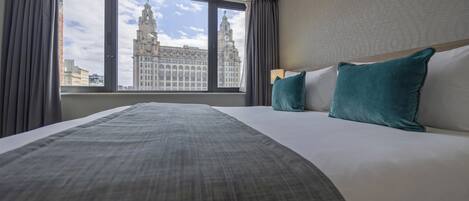 A hotel room with a large bed, a view of a historic building, and a window with curtains.
