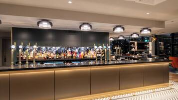 A bar area with a long counter, multiple bottle dispensers, and overhead lighting.