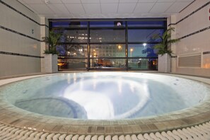 An indoor swimming pool with a tiled edge, large windows, and two potted plants. - Crowne Plaza Liverpool City Centre by IHG (Liverpool)
