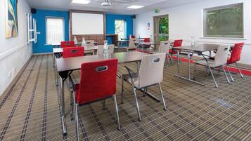 A conference room with tables, chairs, a projector screen, and a whiteboard.