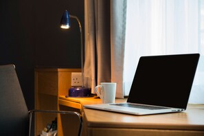 Work comfortably from the desk with a chair nearby, featuring a laptop, a mug, and a desk lamp.