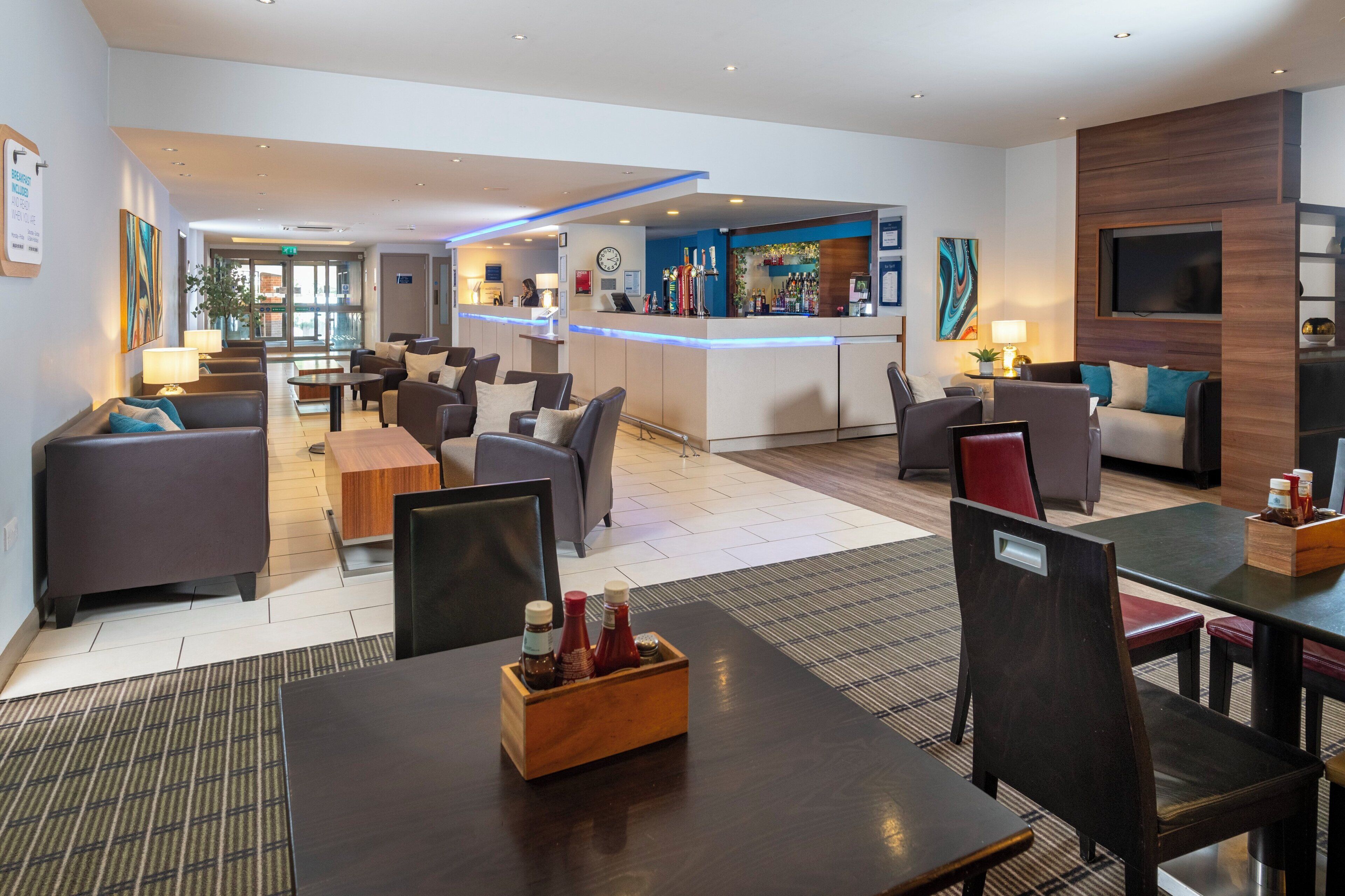A hotel lobby with seating areas, a reception desk, and a bar.
