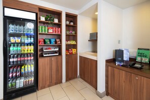 A vending machine stocked with beverages and snacks, a payphone, and a counter with a 'PAY HERE' sign. - Holiday Inn Express Taunton East by IHG (Taunton)