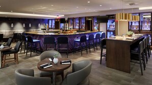 A modern bar area with a bar counter, seating, and a television screen.