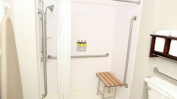Un baño con ducha, inodoro y un pequeño banco de madera.