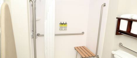 Un baño con ducha, inodoro y un pequeño banco de madera.