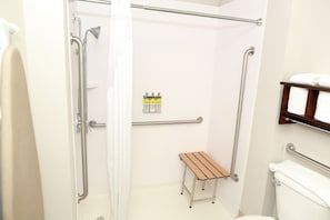 A bathroom with a shower, toilet, and a small wooden bench.