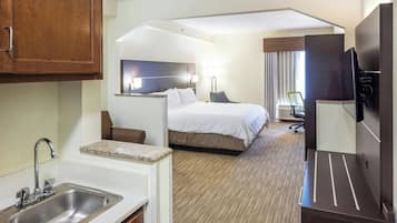 Una habitación de hotel con cama, escritorio, televisor, lavamanos y espejo.
