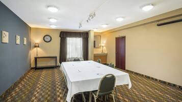 A conference room with a long table, chairs, a clock, and a window with curtains.