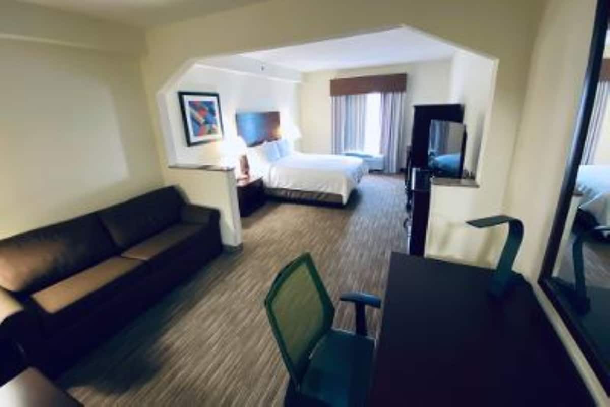 A hotel room with a bed, a desk, a chair, and a sofa.