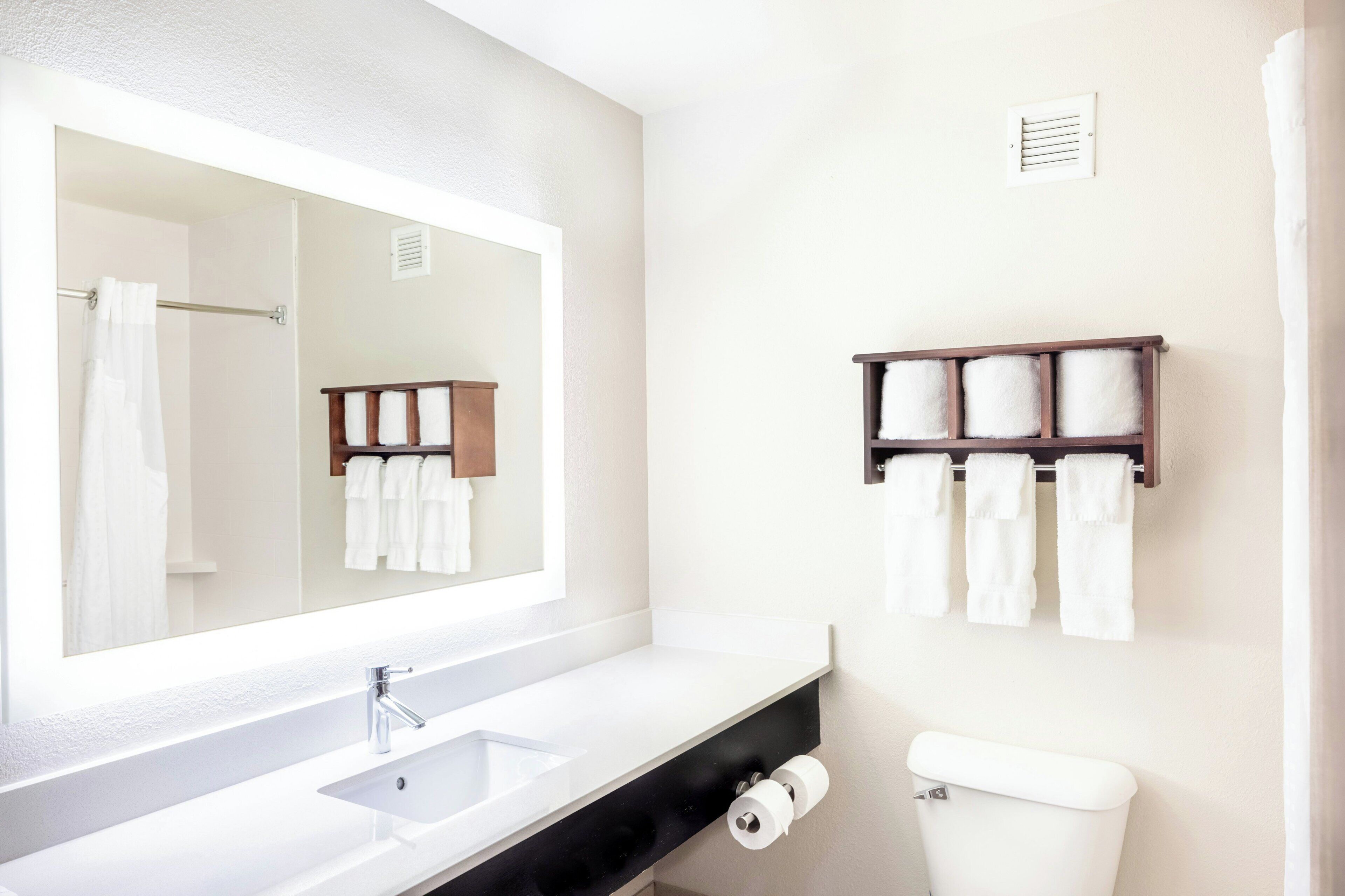 Ein Badezimmer mit großem Spiegel, Waschbecken, Toilette und Handtuchhalter.