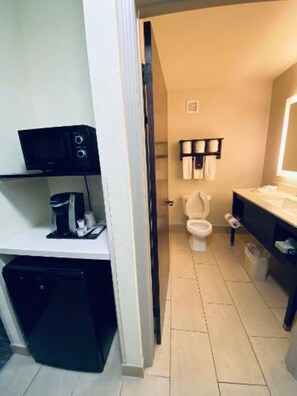 A compact bathroom with a toilet, sink, and a small coffee machine.