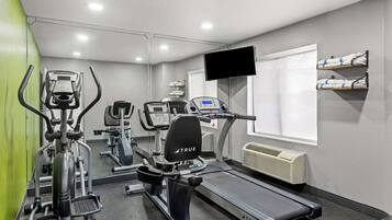 Un gimnasio con cintas de correr, elípticas y una bicicleta estática.