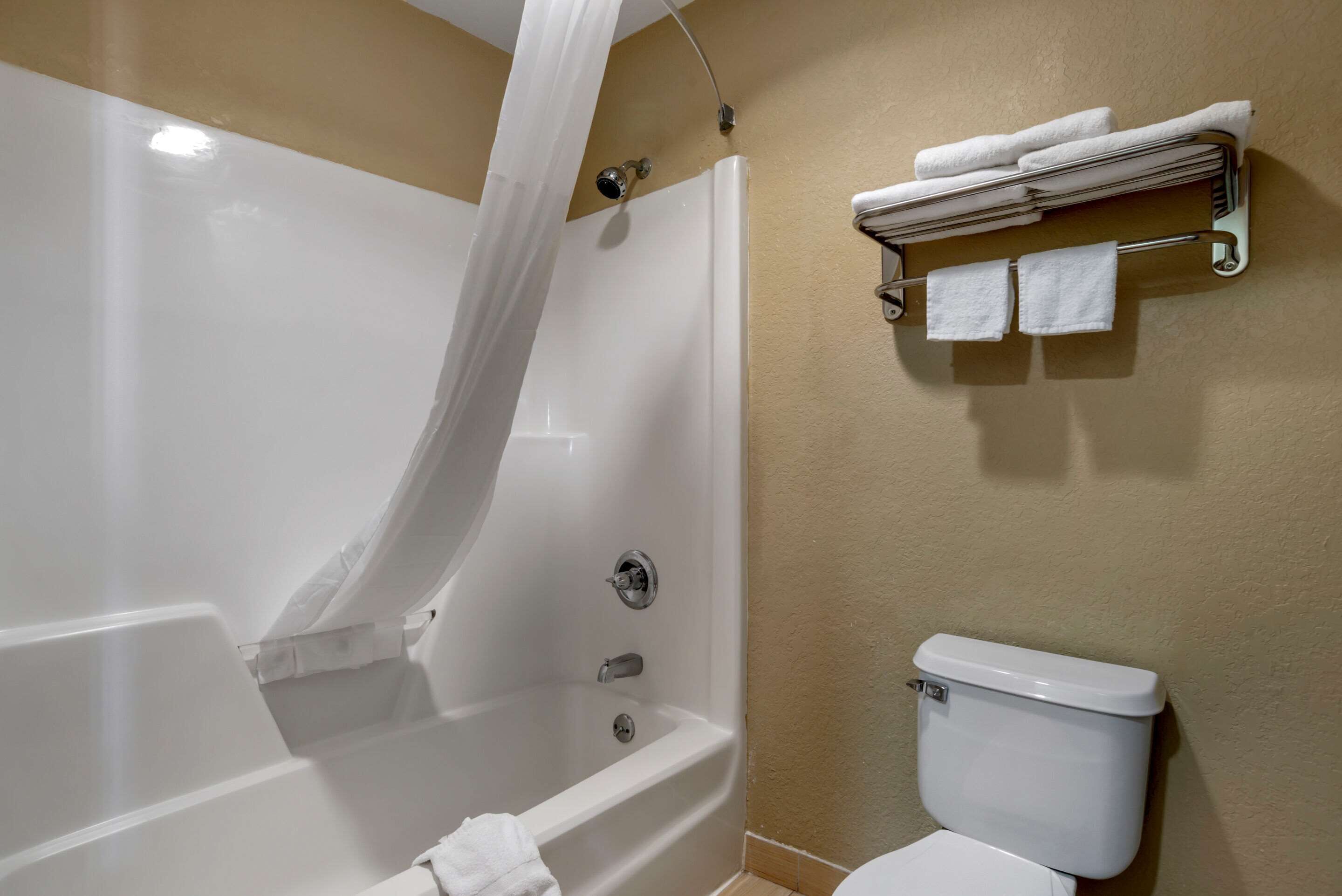 Un baño con bañera, inodoro y toallero con toallas.