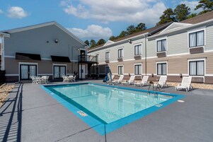 Una piscina al aire libre, sillones reclinables de piscina