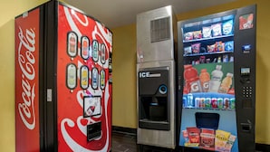 Máquina expendedora con logotipo de Coca-Cola y dispensador de hielo.