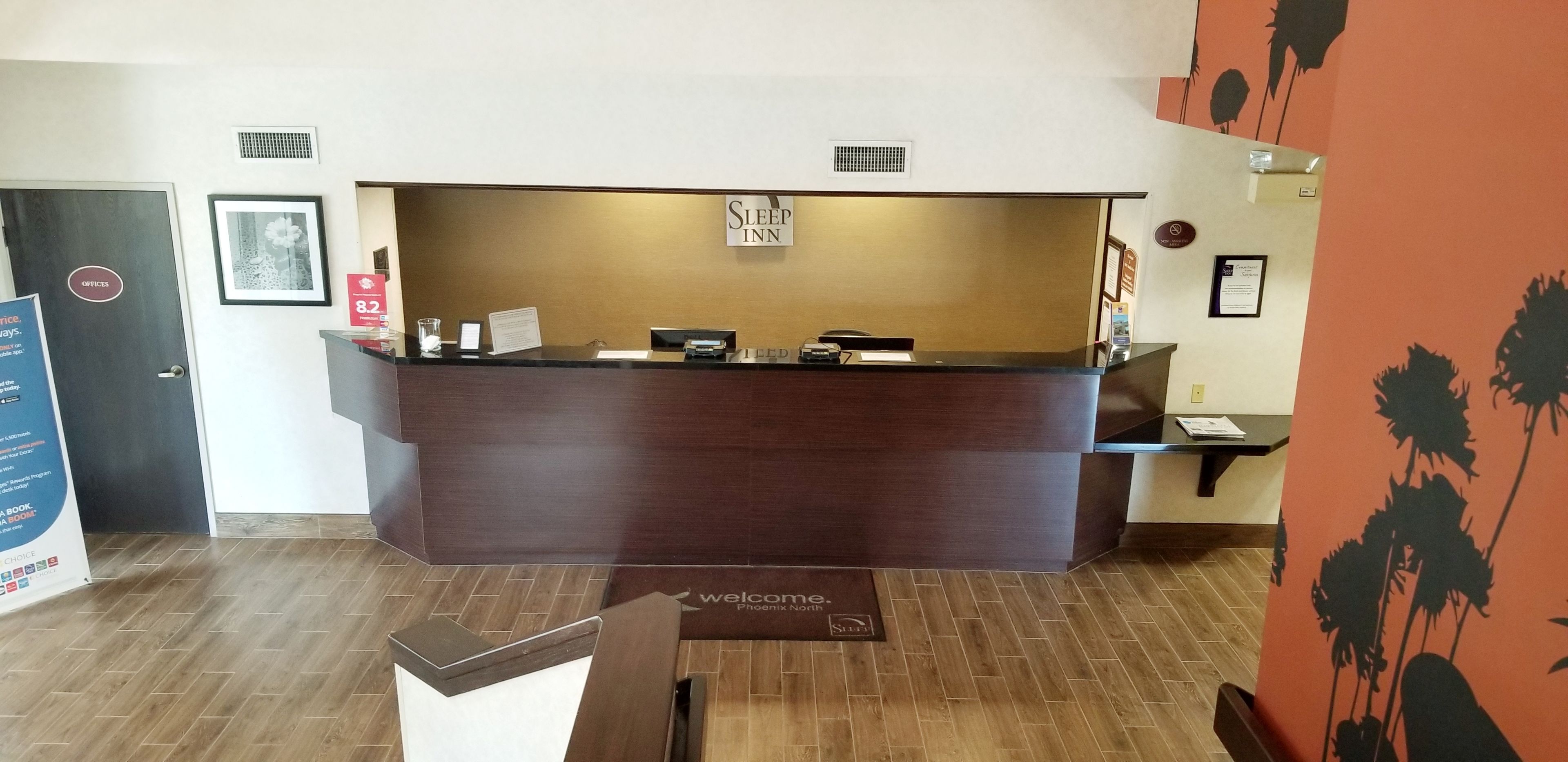 Un mostrador de recepción con un cartel que dice "Sleep Inn" y una alfombra de bienvenida.