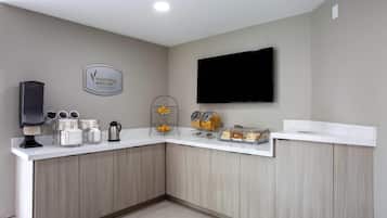 Una cocina moderna con barra americana, una cafetera y un televisor montado en la pared.
