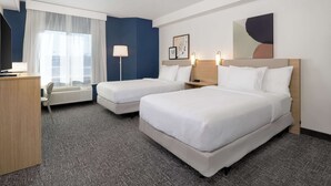 A hotel room with two beds, a desk, a chair, a lamp, and a large window with sheer curtains. - Spark by Hilton Bentonville (Bentonville)