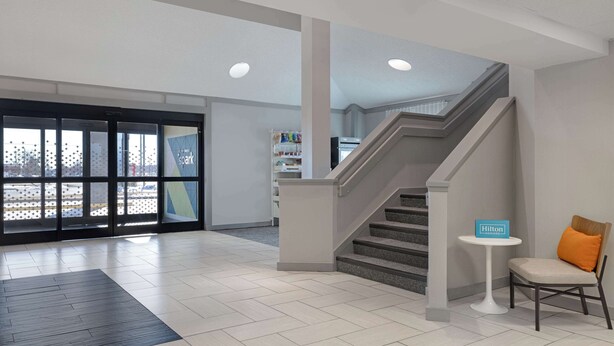 A hotel lobby with a staircase, a reception desk, and a seating area. - Spark by Hilton Bentonville (Bentonville)