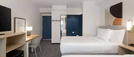 A hotel room with two beds, a desk, a chair, a TV, and a mirror.