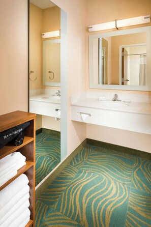 A bathroom with a sink, mirror, towel rack, and a hair dryer shelf. - SpringHill Suites Bentonville (Bentonville)