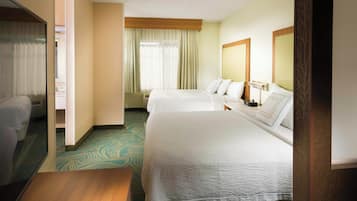 Habitación de hotel con dos camas, una mesita de noche de madera, un espejo grande y una ventana con cortinas.