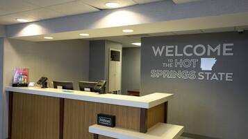 Een receptiebalie met een bord waarop staat 'WELCOME TO THE HOT SPRINGS STATE' en een 'Hilton Honors' badge.