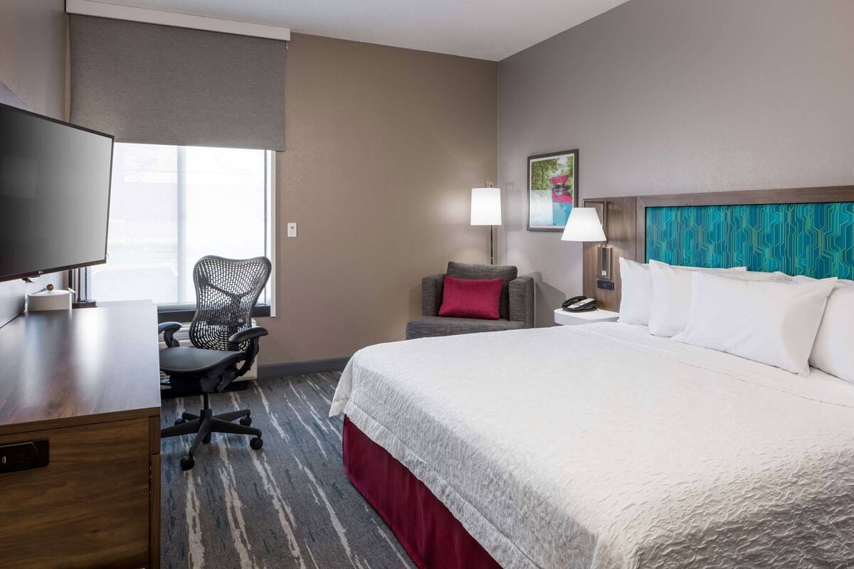 Une chambre d’hôtel équipée d’un lit, d’un bureau, d’une chaise et d’un téléviseur.