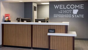 A reception desk with a "Welcome to the Hot Springs State" sign, a "Hilton Honors" sign, and a phone.