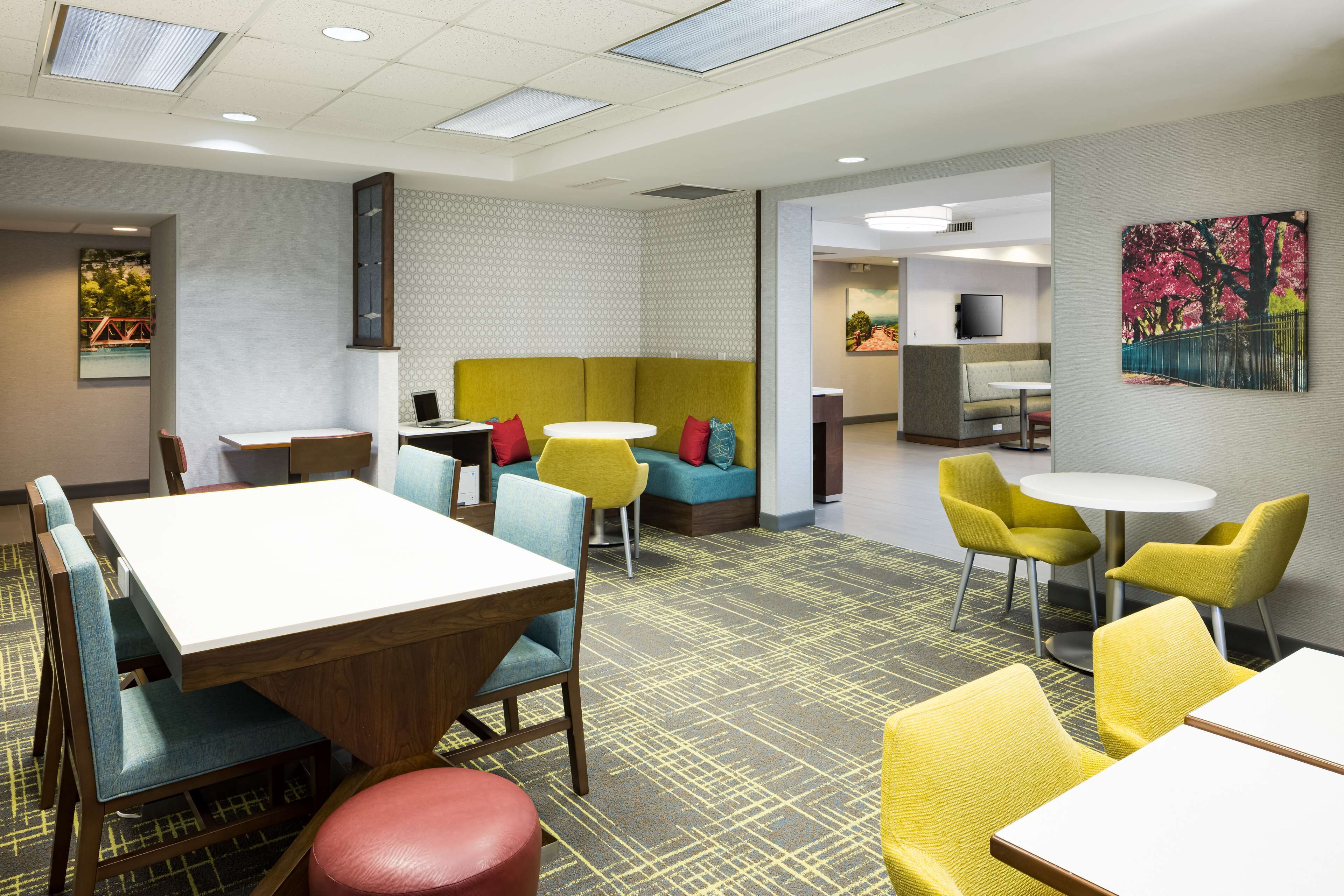 Un hall d’hôtel moderne doté d’un espace détente comprenant un canapé et des fauteuils, une petite table et un téléviseur posé sur un meuble.