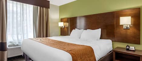 Una habitación de hotel con una cama grande, dos lámparas de noche, un teléfono y una ventana con cortinas.