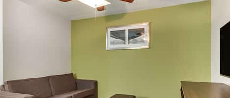 Una habitación con un sofá marrón, un mueble de madera y un cuadro en la pared.